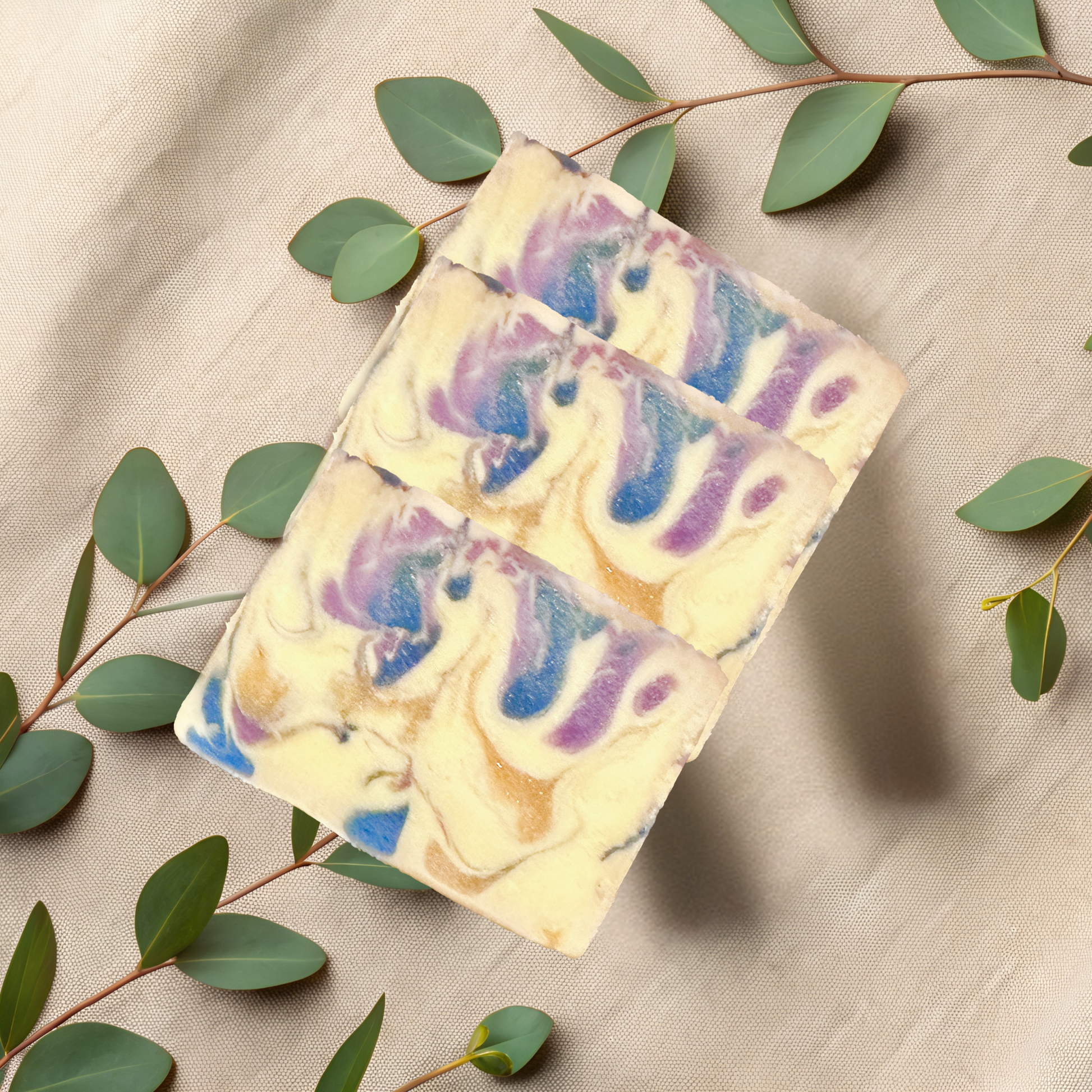 Colorful soap bars with swirl patterns on a beige fabric background with green leaves.
