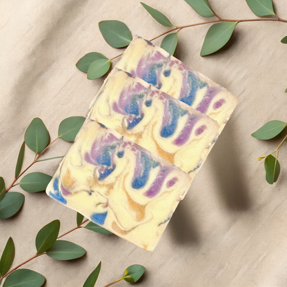Colorful soap bars with swirl patterns on a beige fabric background with green leaves.