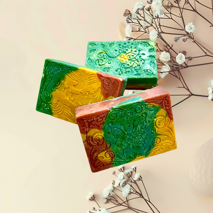 Three colorful soap bars with decorative patterns on a light background with white flowers.