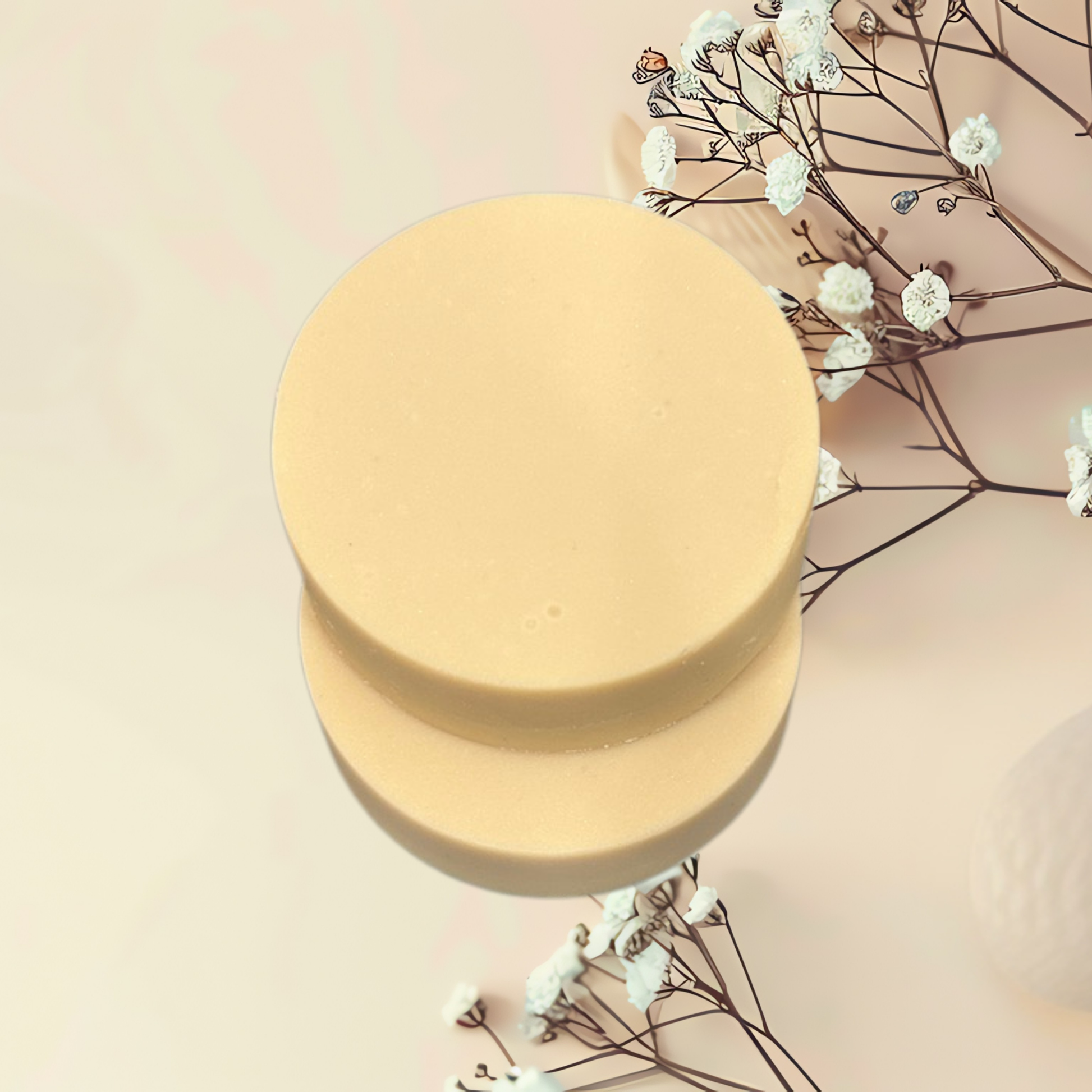 Round yellow soap bar with dried flowers on a light pink background