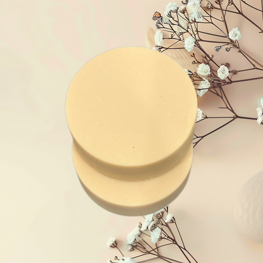 Round yellow soap bar with dried flowers on a light pink background