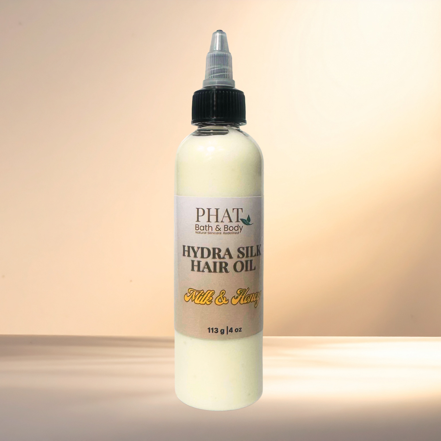 Bottle of PHAT Bath & Body Hydra Silk Hair Oil on a gradient background