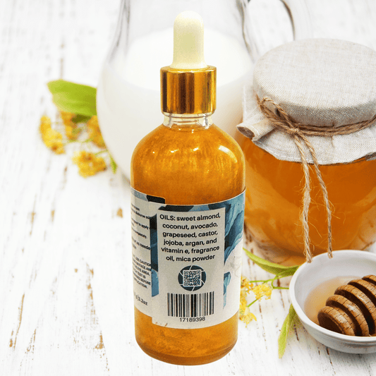 Bottle of milk and honey shimmer body oil with a label on a white surface