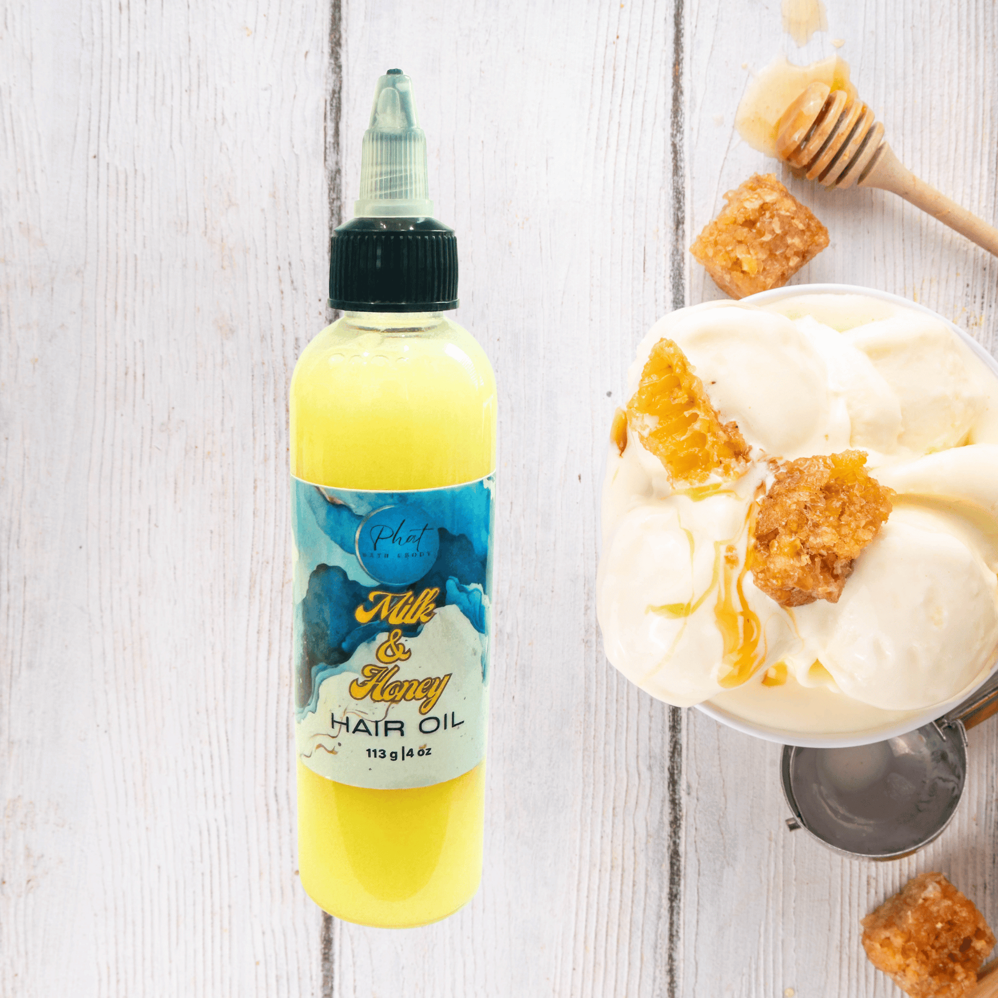 Bottle of hair oil next to a bowl of ice cream with honeycomb on a wooden surface