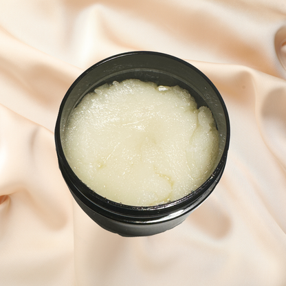 Black container of white scrub on a soft pink fabric background