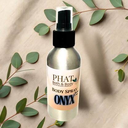 Body spray bottle labeled 'PHAT Bath & Body' on a beige fabric background with green leaves.
