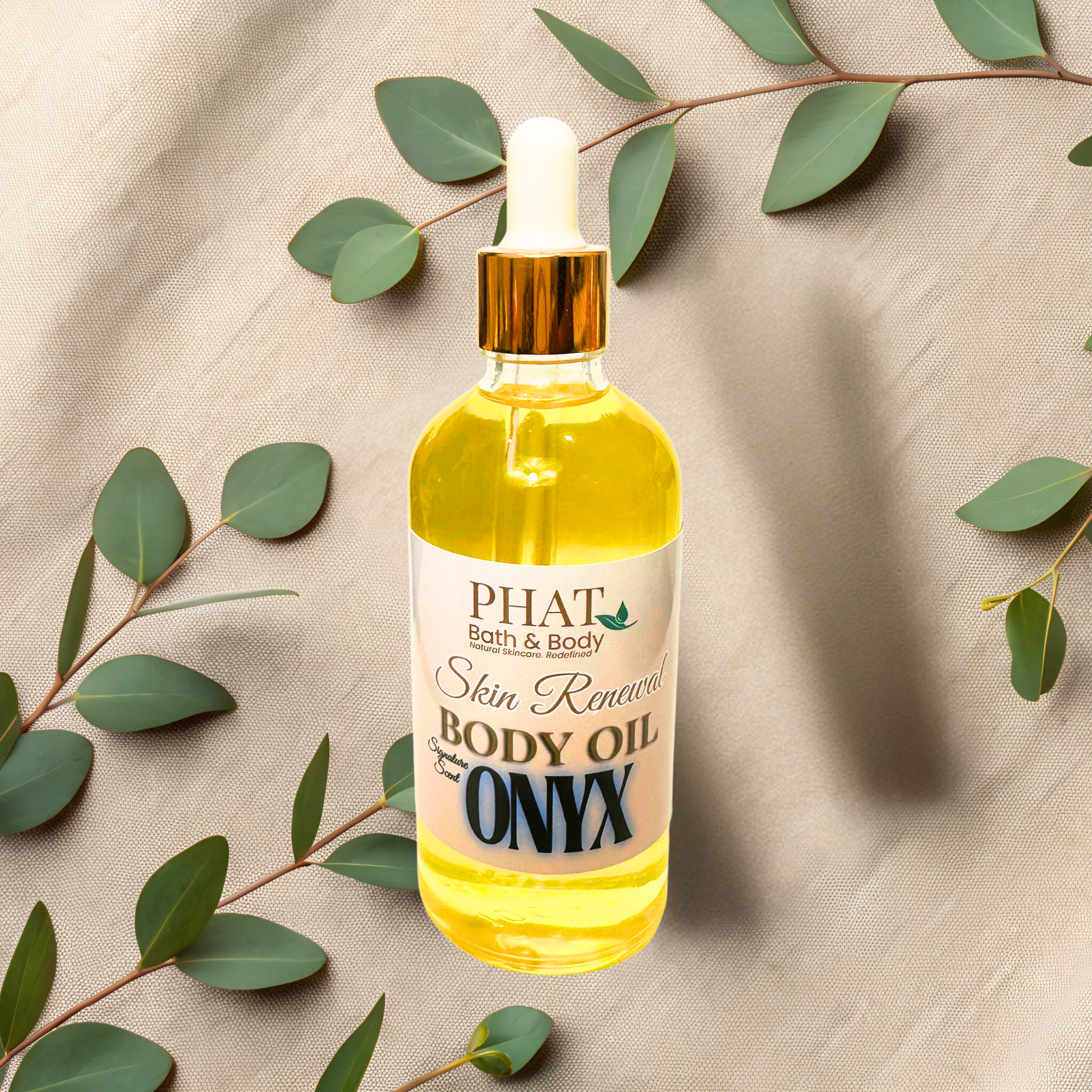 Bottle of PHAT Bath & Body Onyx Skin Renewal Body Oil with green leaves on a beige fabric background