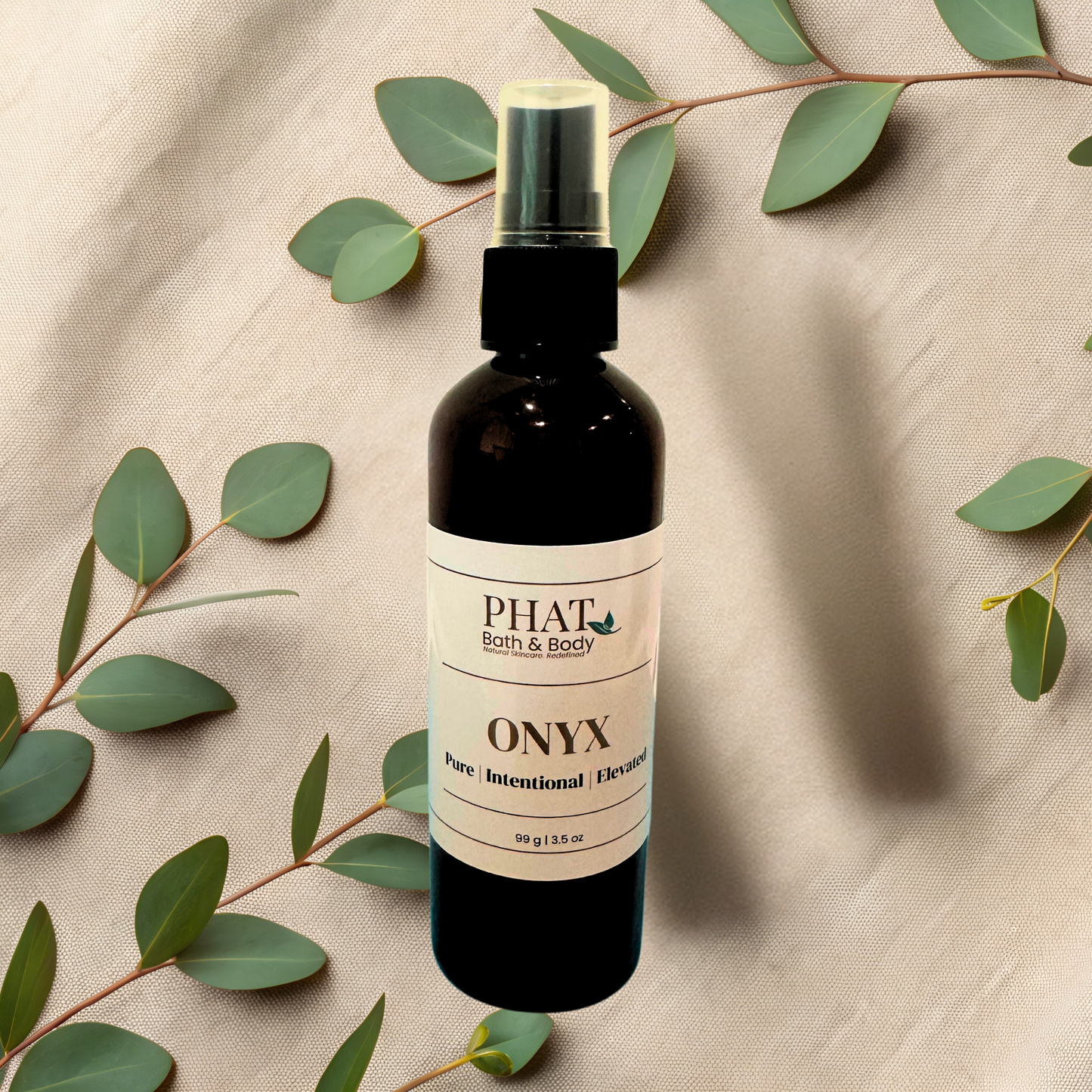 Bottle of 'Onyx' by Phat Bath & Body on a beige fabric background with green leaves.