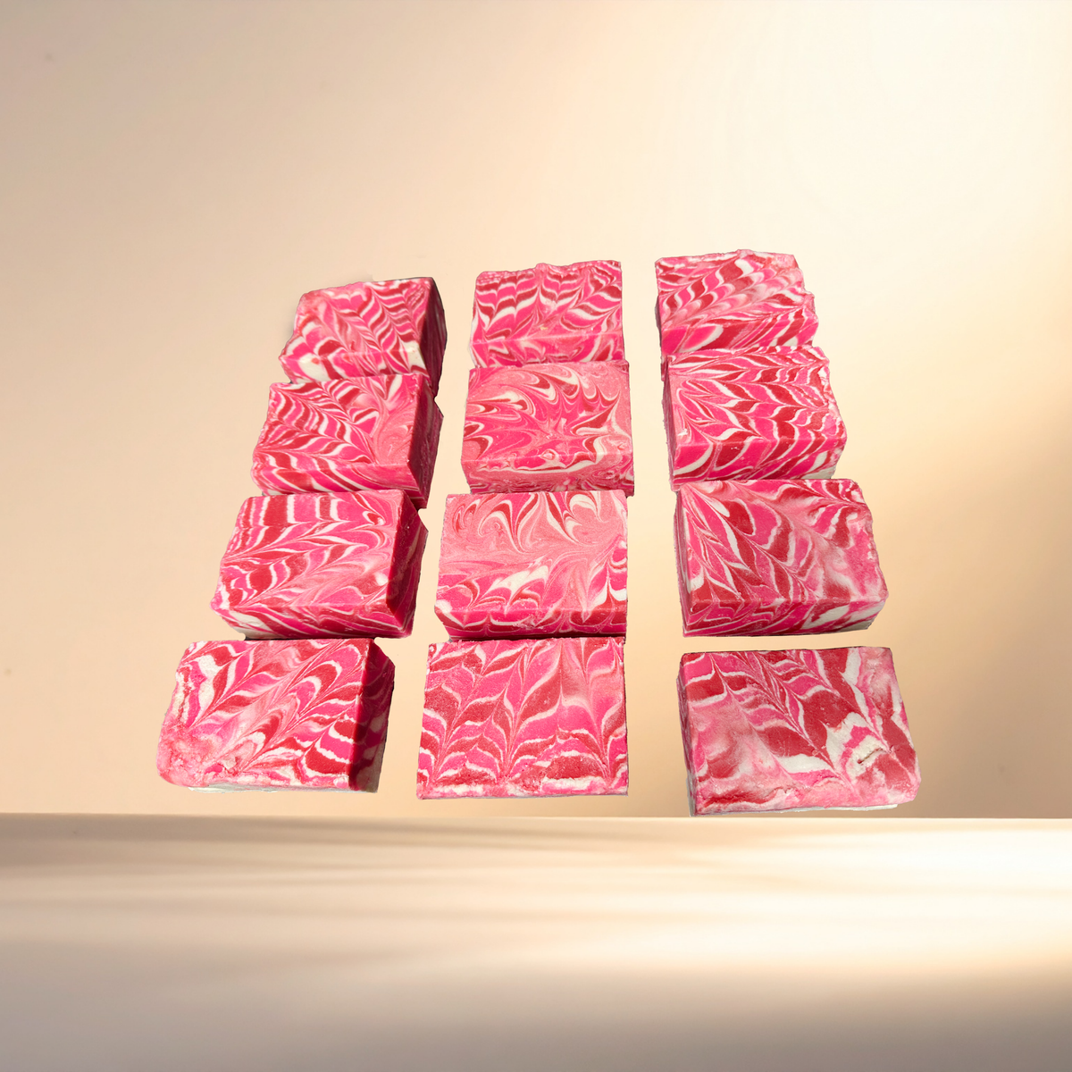Pink marbled soap bars arranged in a grid on a beige background