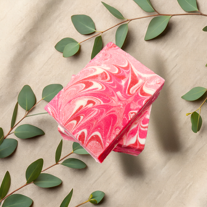 Pink marbled soap bars on a beige fabric background with green leaves