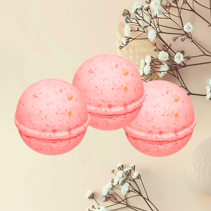 Three pink bath bombs with orange specks on a beige background with white flowers.