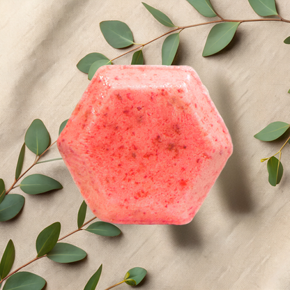 Hexagonal pink shower bomb with green leaves on a beige fabric background