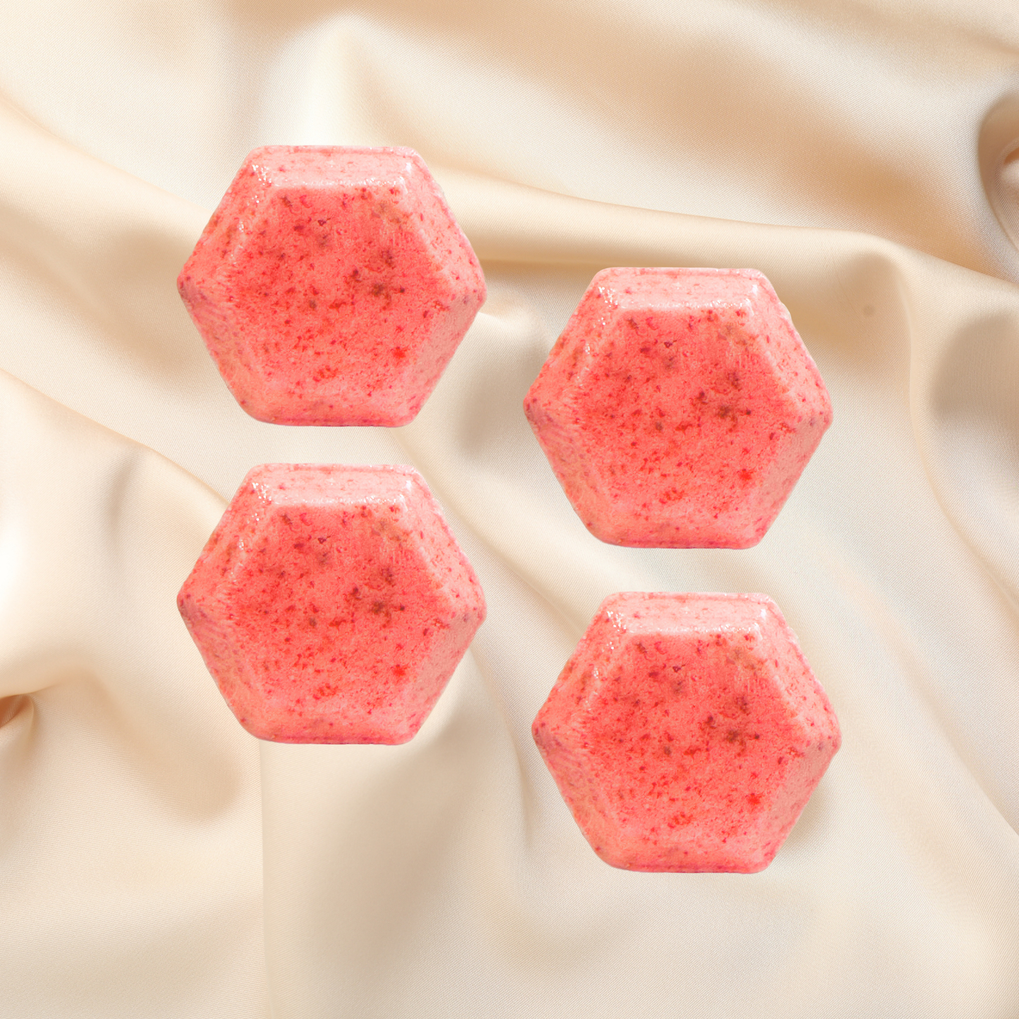 Four pink hexagonal shower bombs on a beige fabric background