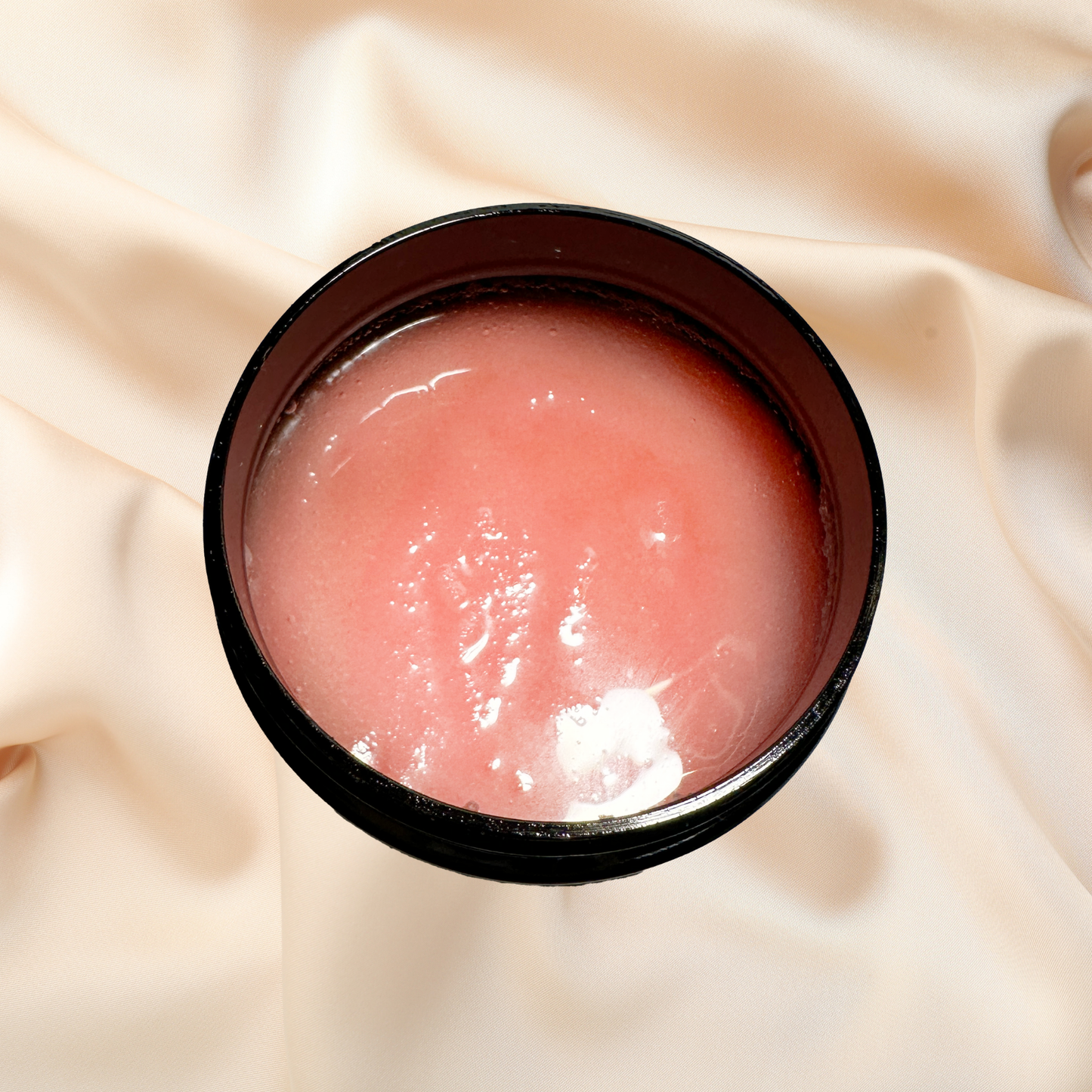 Pink scrub in a black container on a beige fabric background