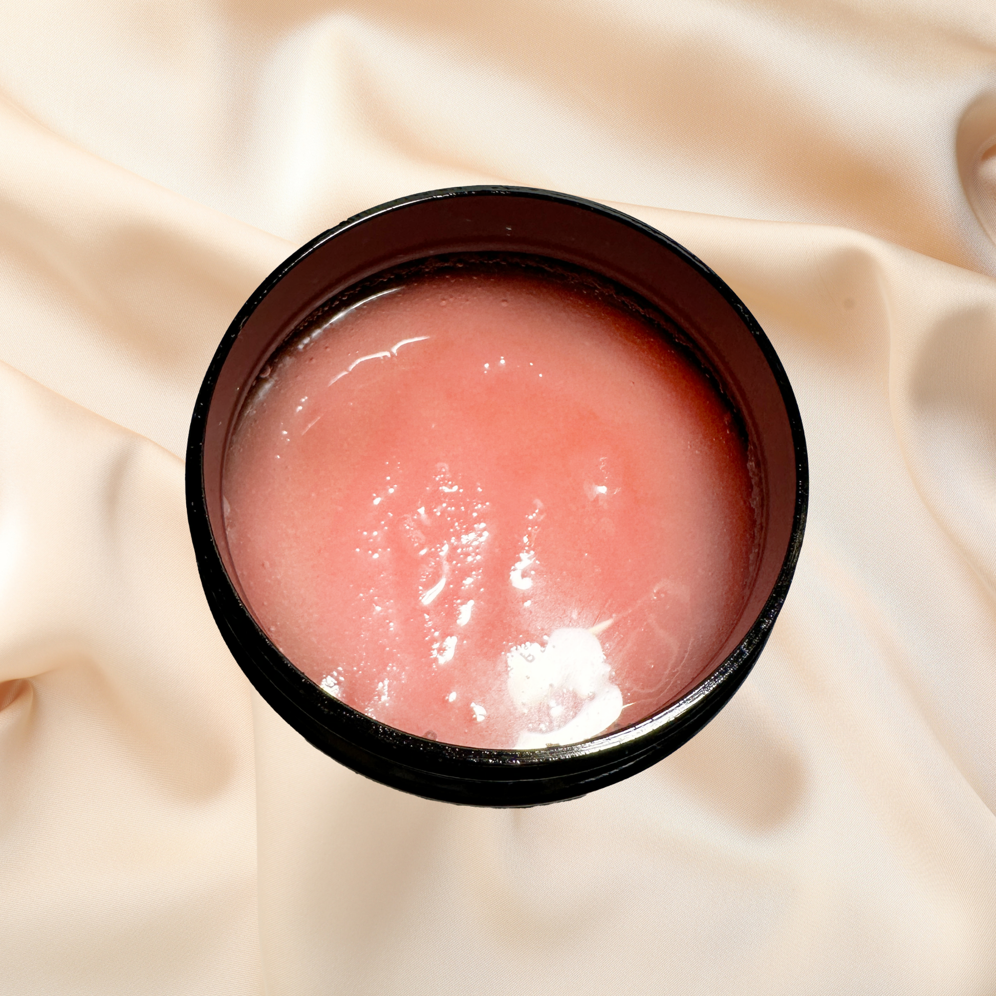 Pink scrub in a black container on a beige fabric background