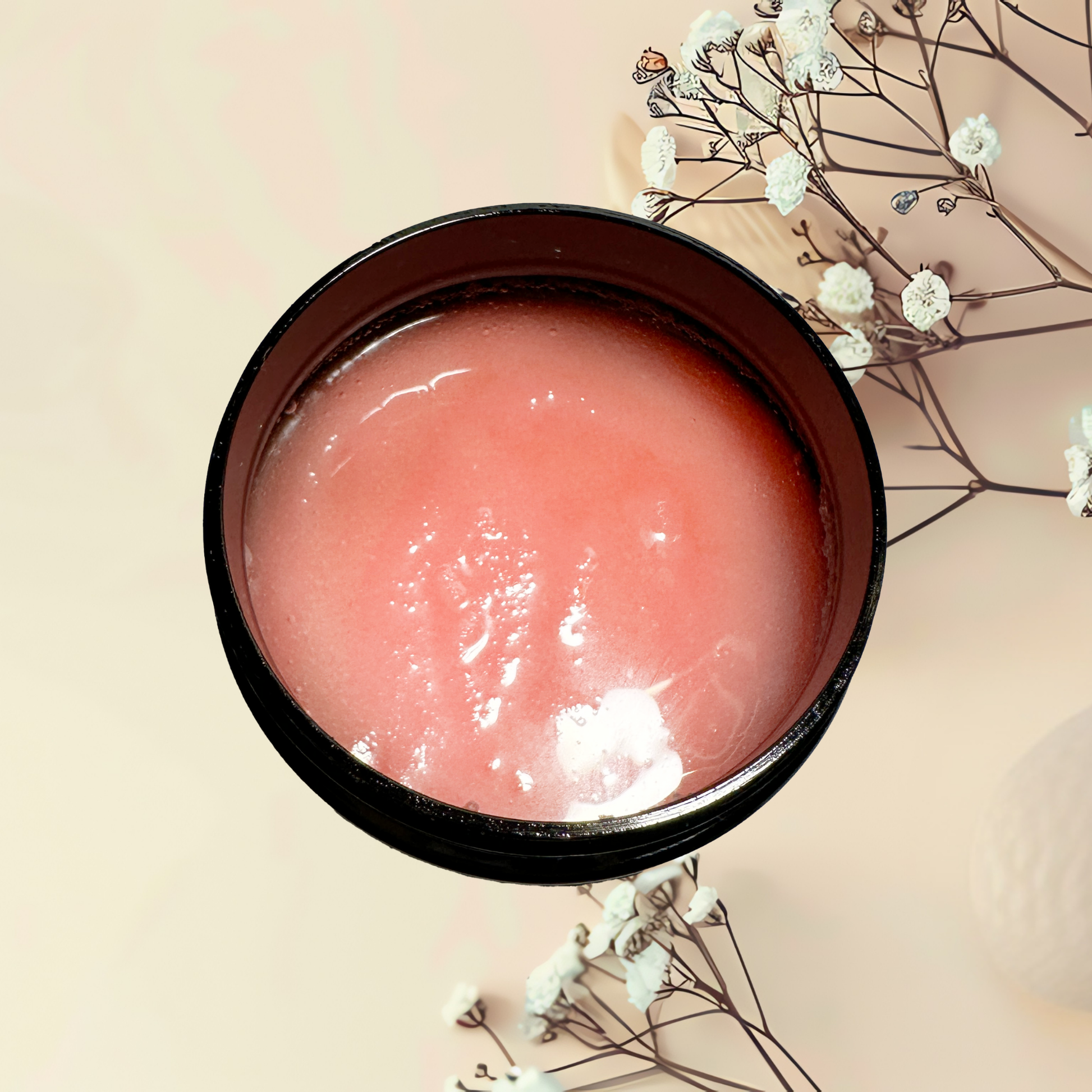 Pink scrub in a black container with white flowers on a beige background