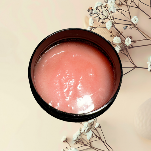 Pink scrub in a black container with white flowers on a beige background
