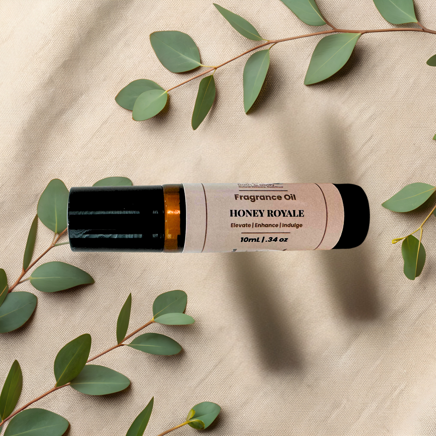 A 10ml bottle of Honey Royale fragrance oil, styled on a beige textured fabric background with green eucalyptus leaves.