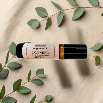 Lavender essential oil roller bottle with a black cap and a cream label, styled on a beige fabric background with green eucalyptus leaves.