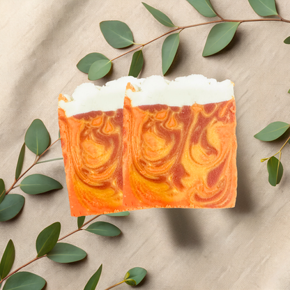 Marbled orange and white soap bar with green leaves on a beige fabric background