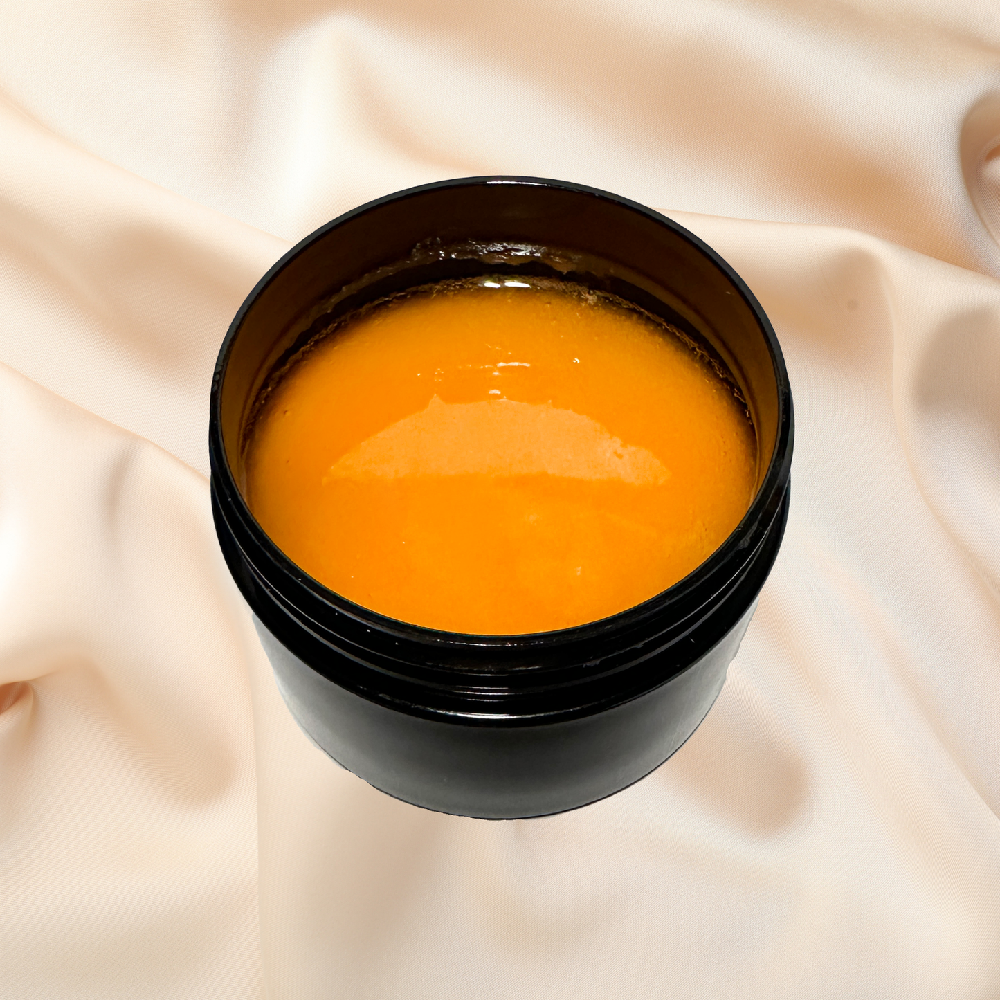 Black container with orange scrub on a beige fabric background