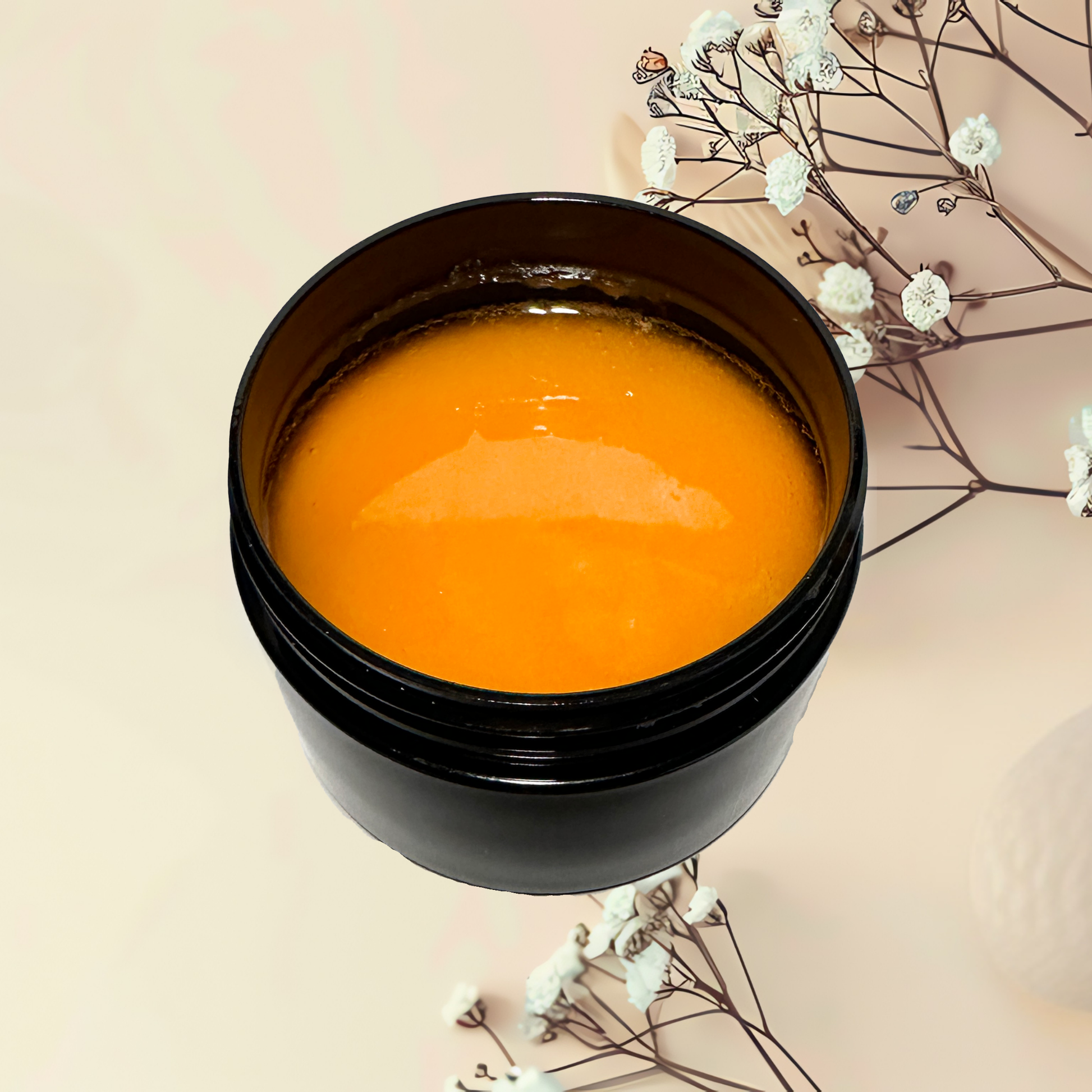 Black container with orange scrub on a beige background with white flowers