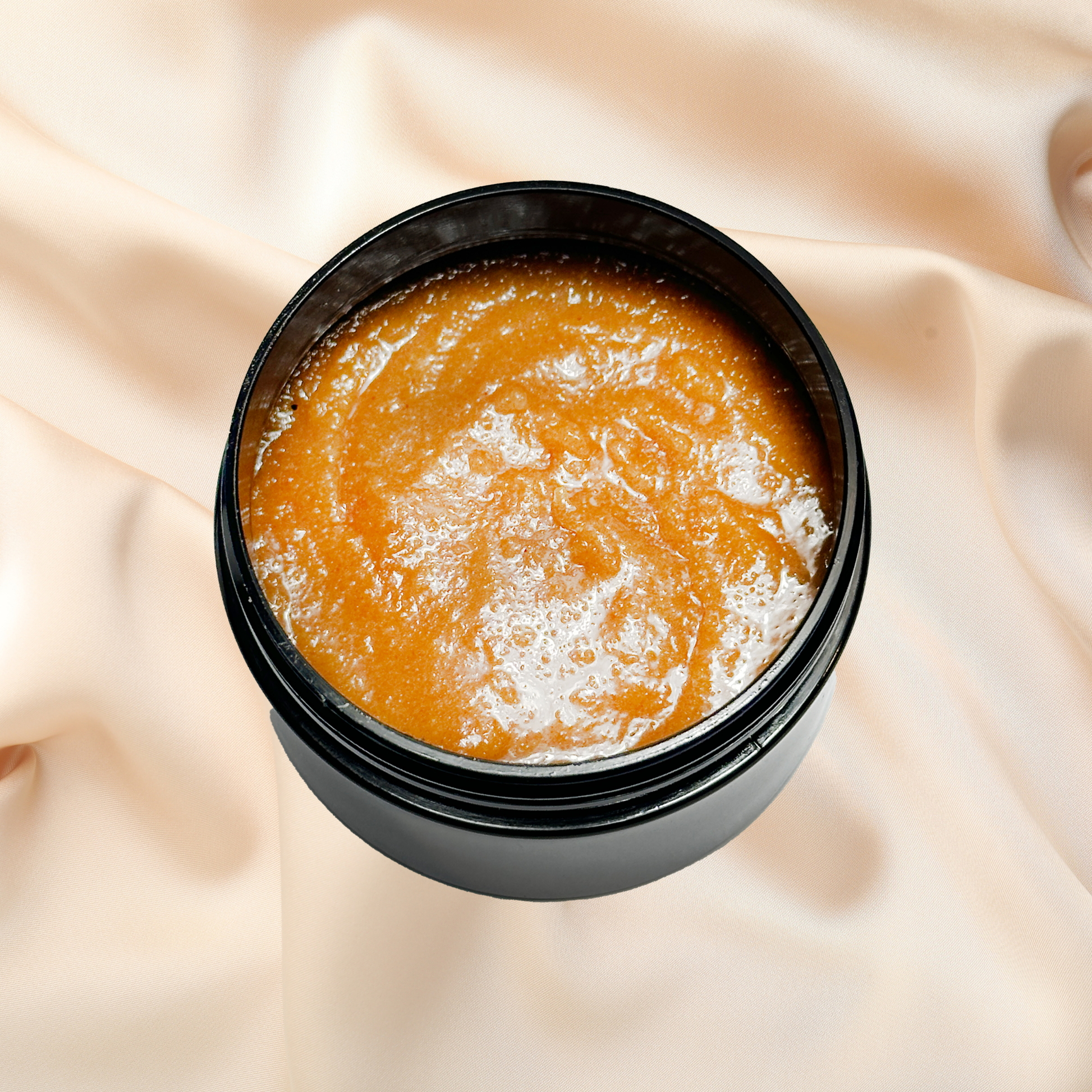 Black container with orange scrub on a beige fabric background