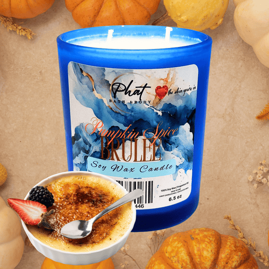 Candle with a blue container and pumpkin spice brulee label, surrounded by pumpkins and a bowl of creme brèleé.