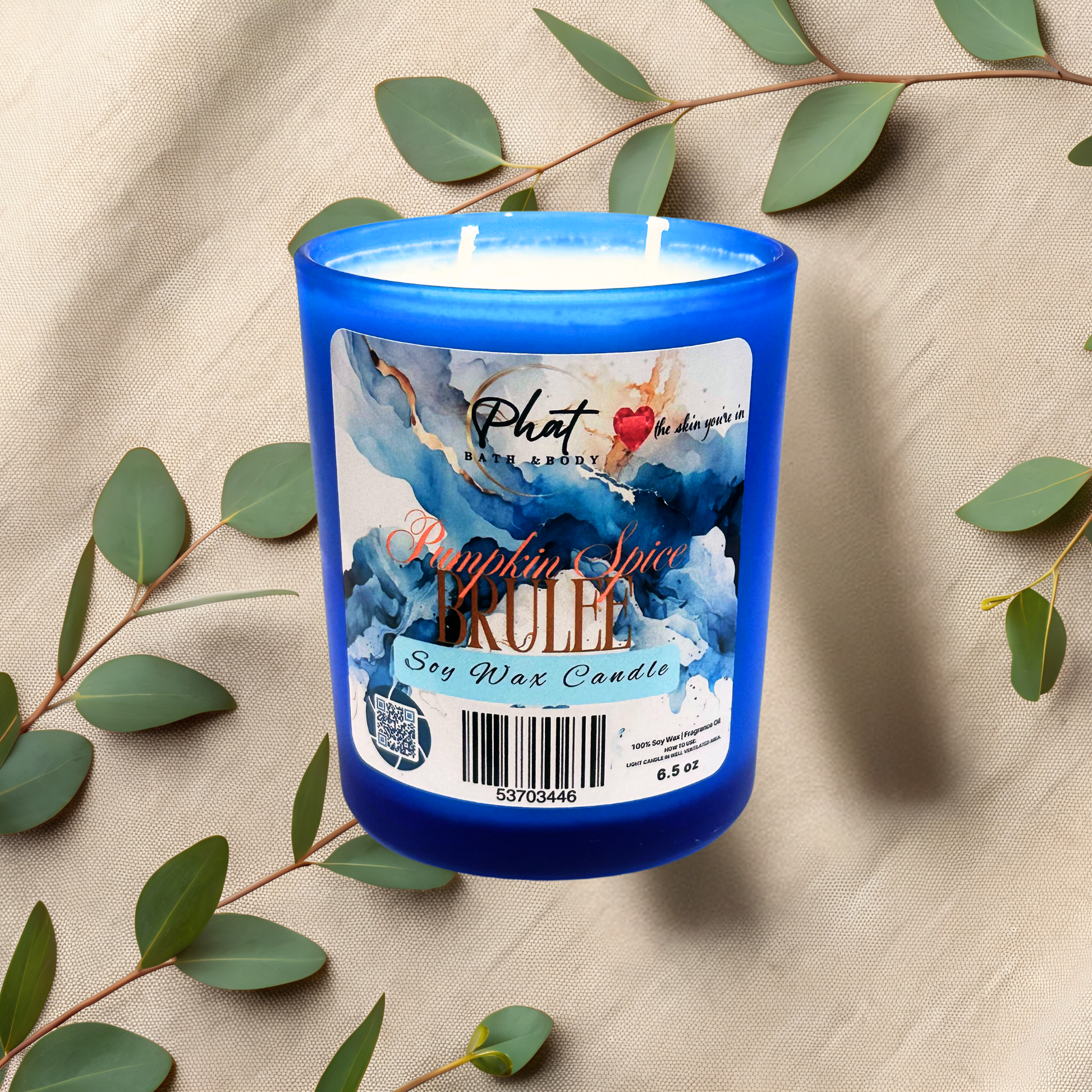 Blue candle with a label on a beige fabric background with green leaves