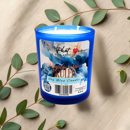 Blue candle with a label on a beige fabric background with green leaves