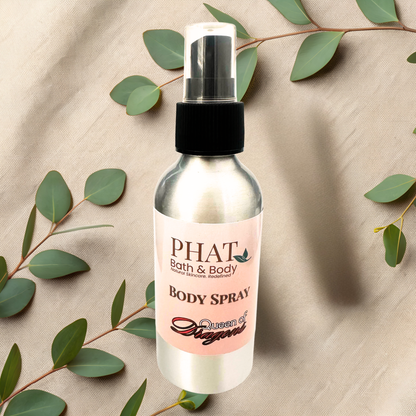 Body spray bottle with 'PHAT Bath & Body' label on a beige fabric background with green leaves.