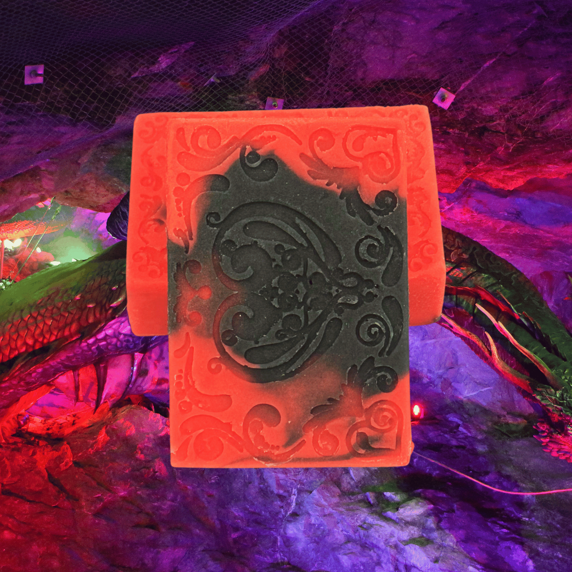 Decorative red and black bar soaps with intricate design on a colorful, dragon-themed background.