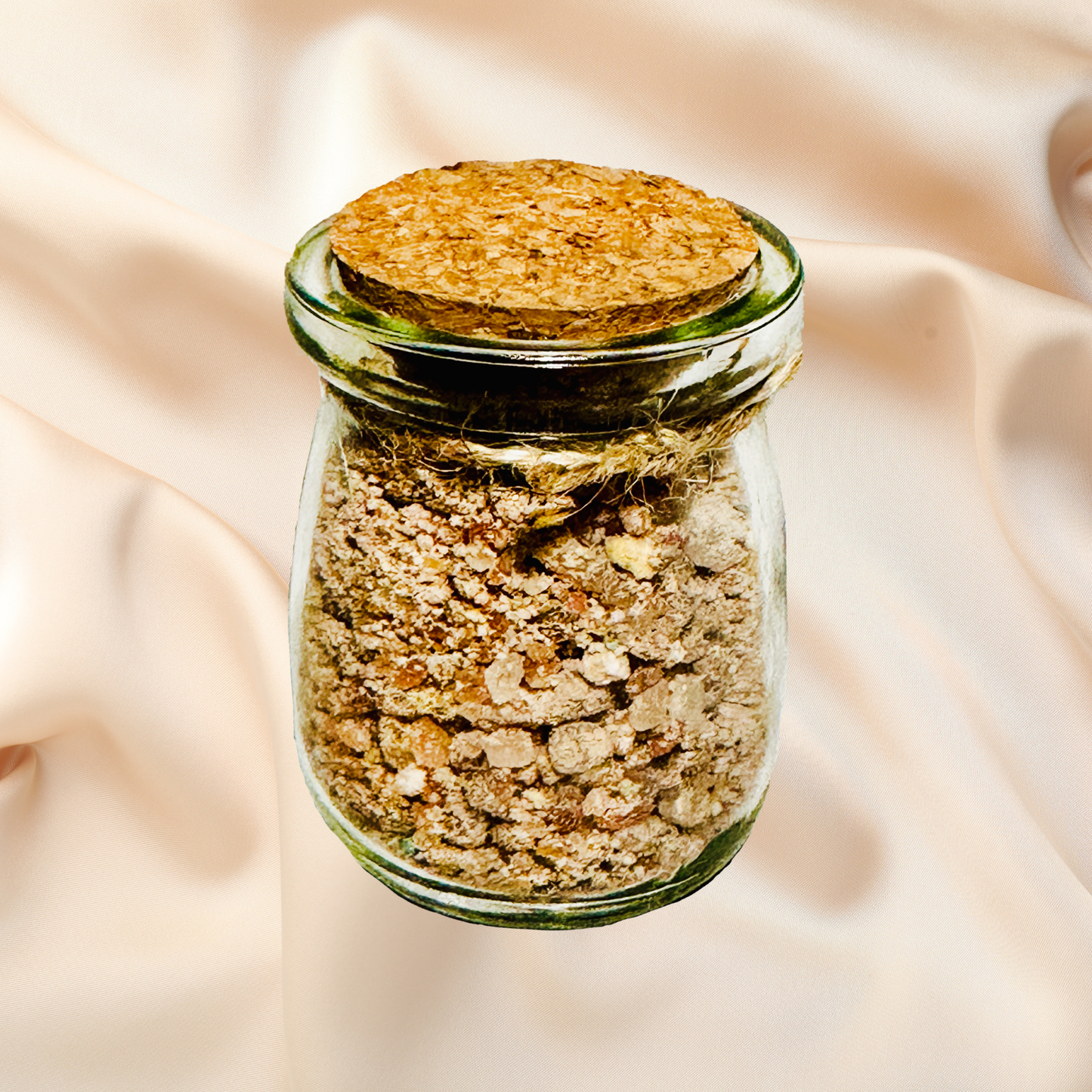 Glass jar with cork lid containing a bath salts on a beige fabric background