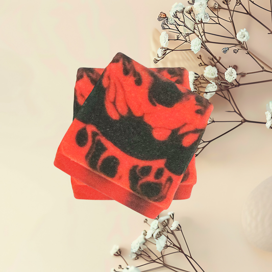 Red and black soap bars with a paw print design on a beige background with white flowers.