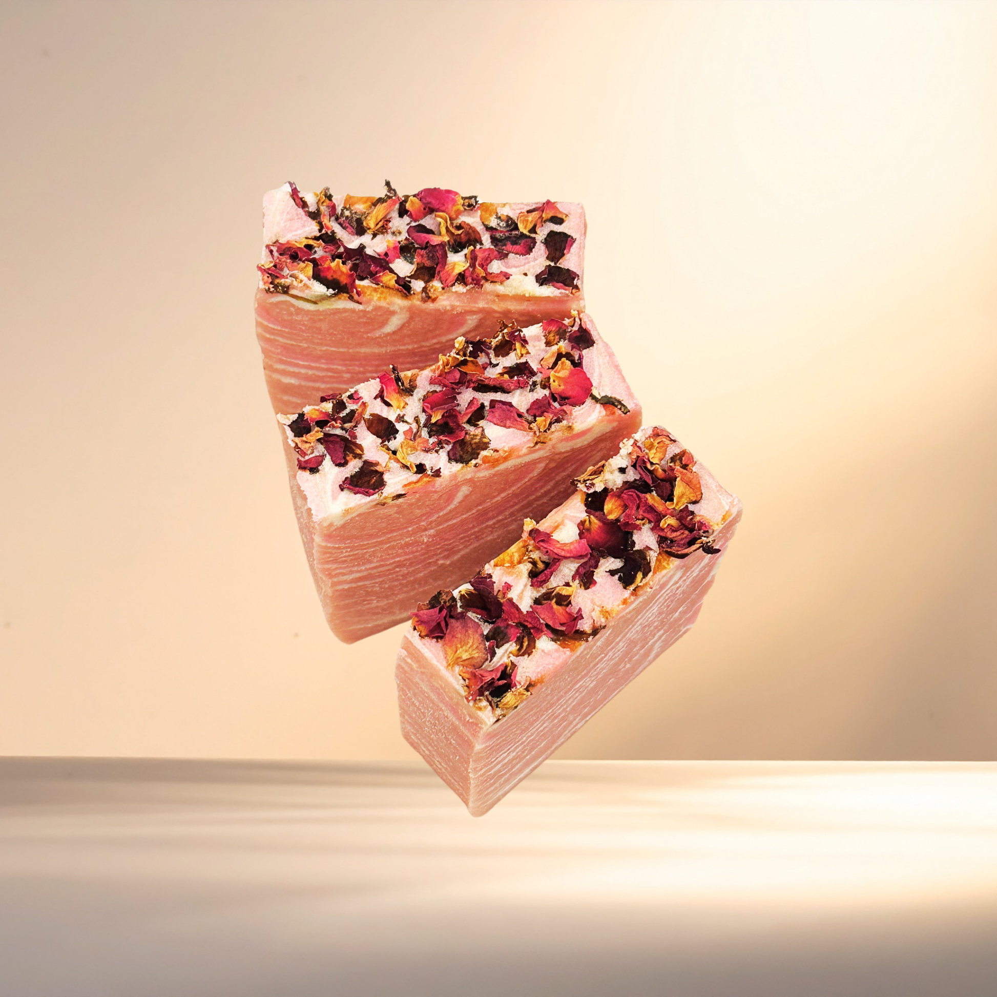 Three rectangular soap bars with floral toppings on a gradient background