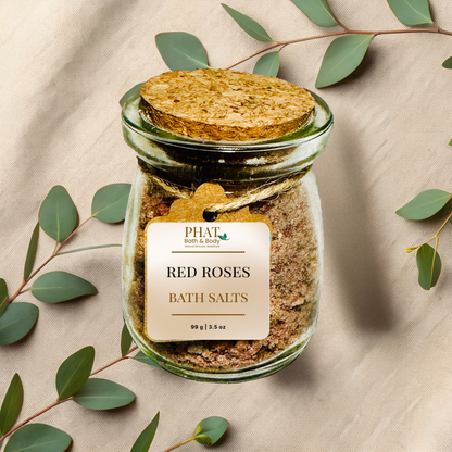 Jar of 'red roses' bath salts with a cork lid on a beige fabric background with eucalyptus leaves.