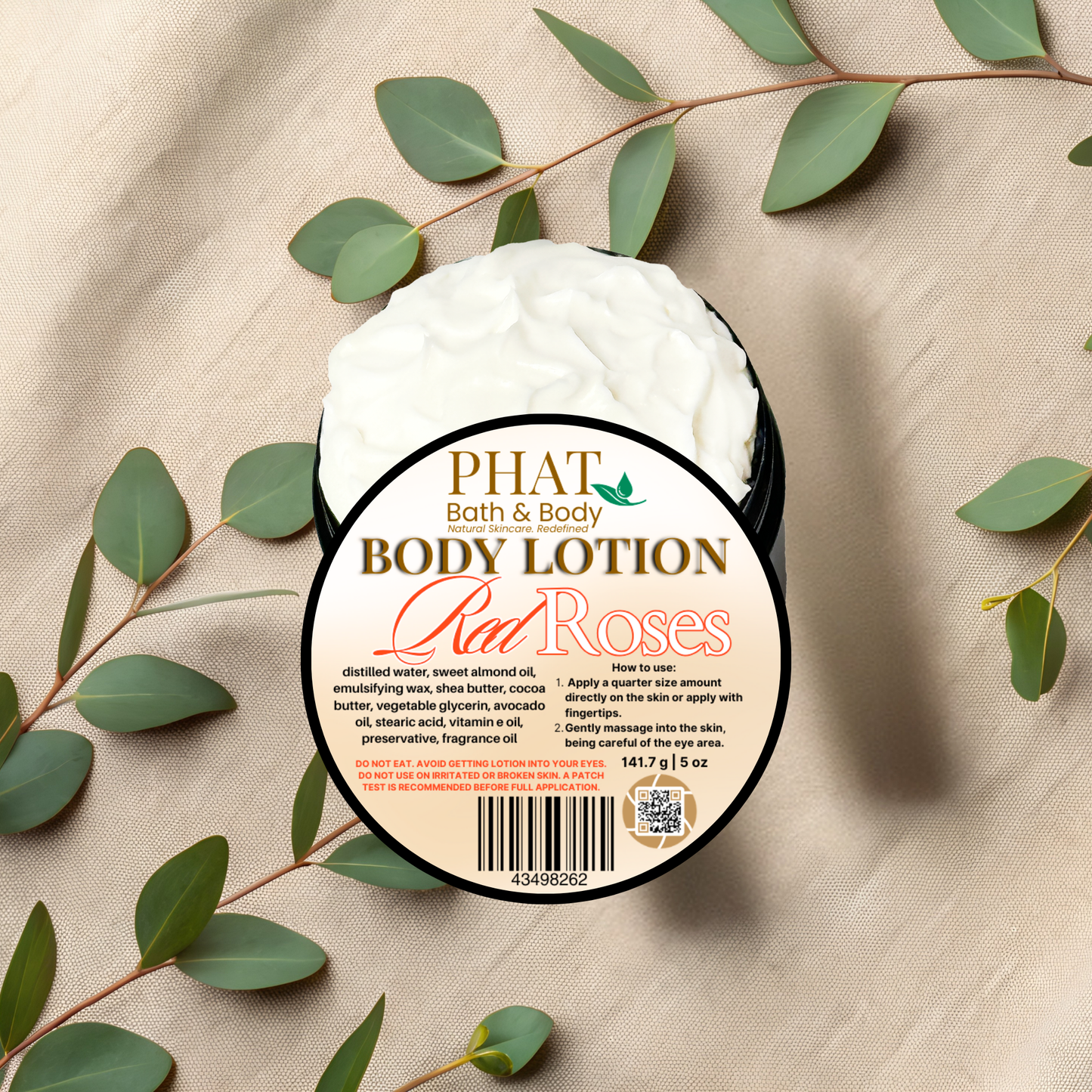 Body lotion container labeled 'Red Roses' from Phat Bath & Body on a beige fabric background with green leaves.