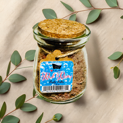 Jar of bath salts with a label on a beige fabric background with green leaves.