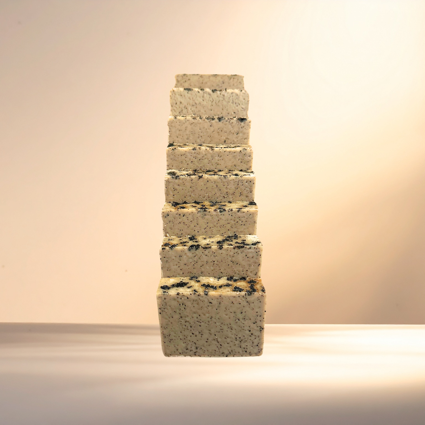 Stack of square soaps with a textured surface on a neutral background