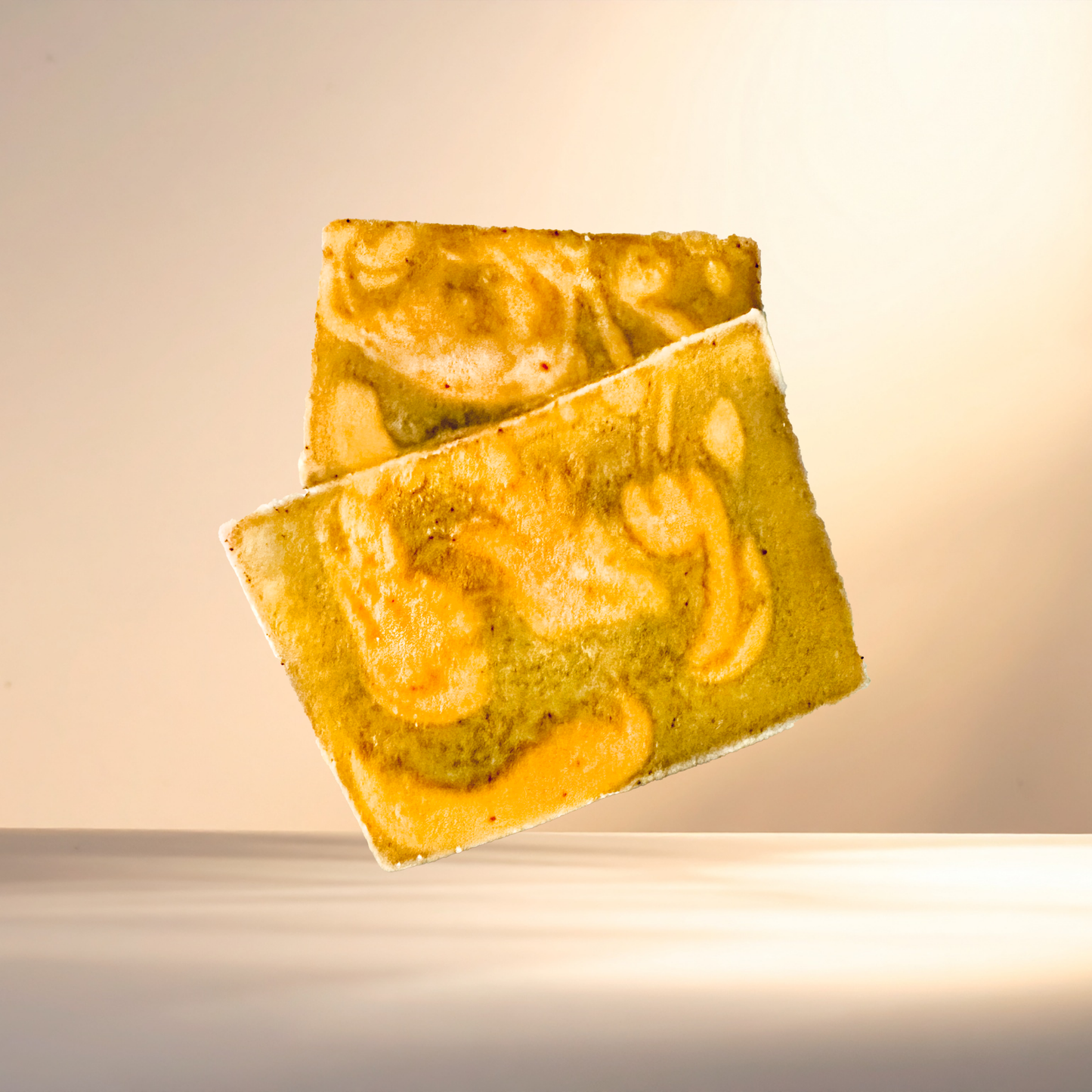 Two marbled soap bars on a reflective surface with a warm glow