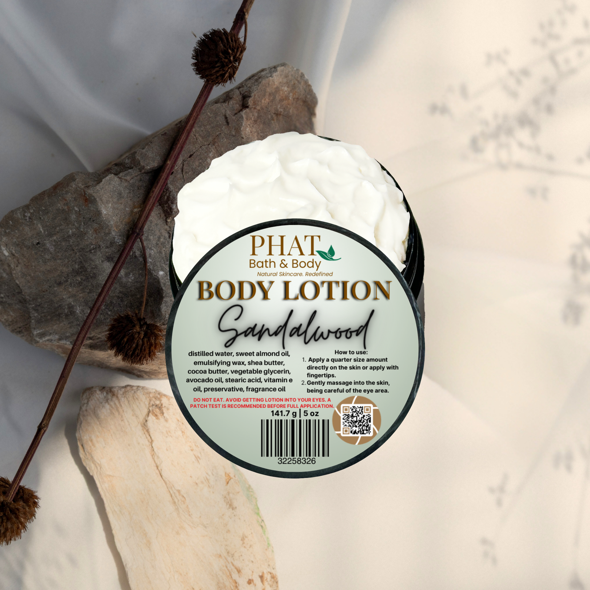 Body lotion container labeled 'Sandalwood' by PHAT Bath & Body on a natural stone background.