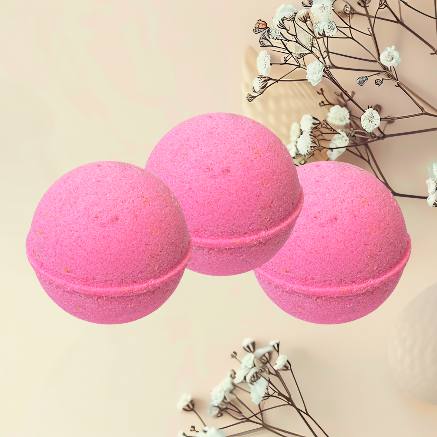 Three pink bath bombs with dried flowers on a beige background