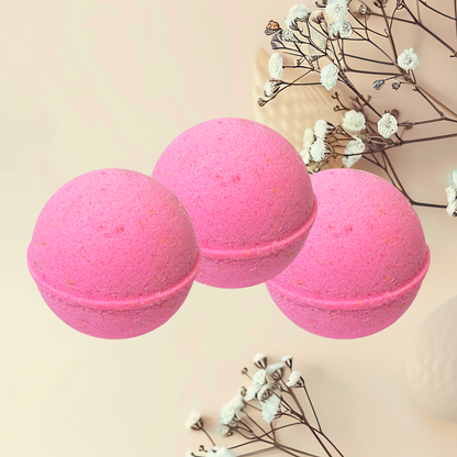 Three pink bath bombs with dried flowers on a beige background