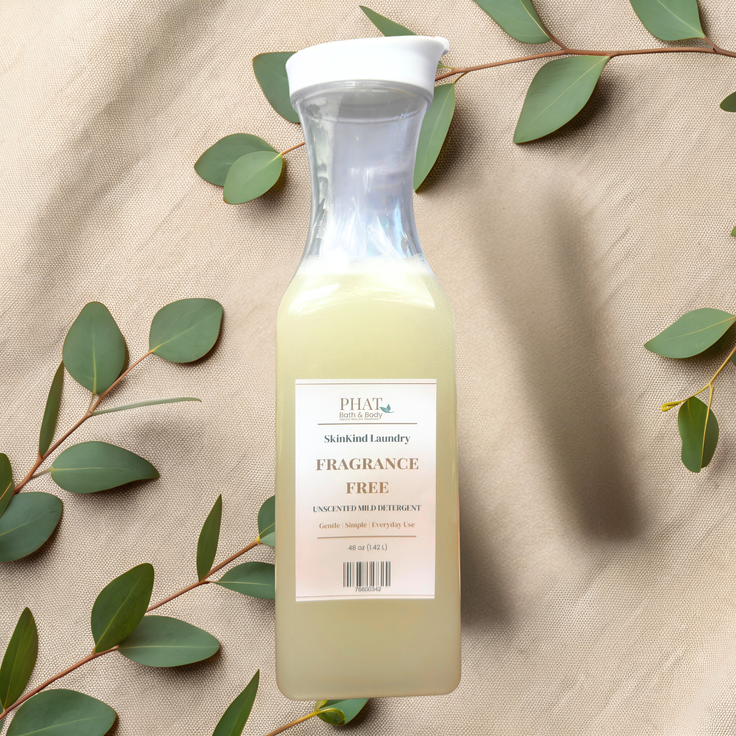 Bottle of fragrance free laundry detergent on a beige fabric background with green leaves.