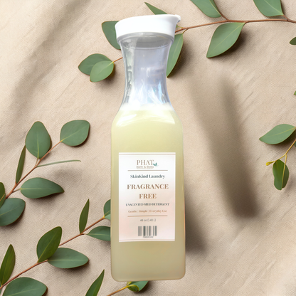 Bottle of fragrance free laundry detergent on a beige fabric background with green leaves.