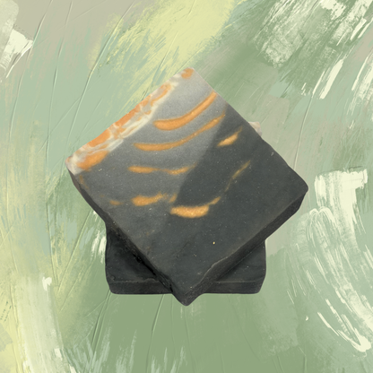 Black soap bar with orange swirls on a green textured background