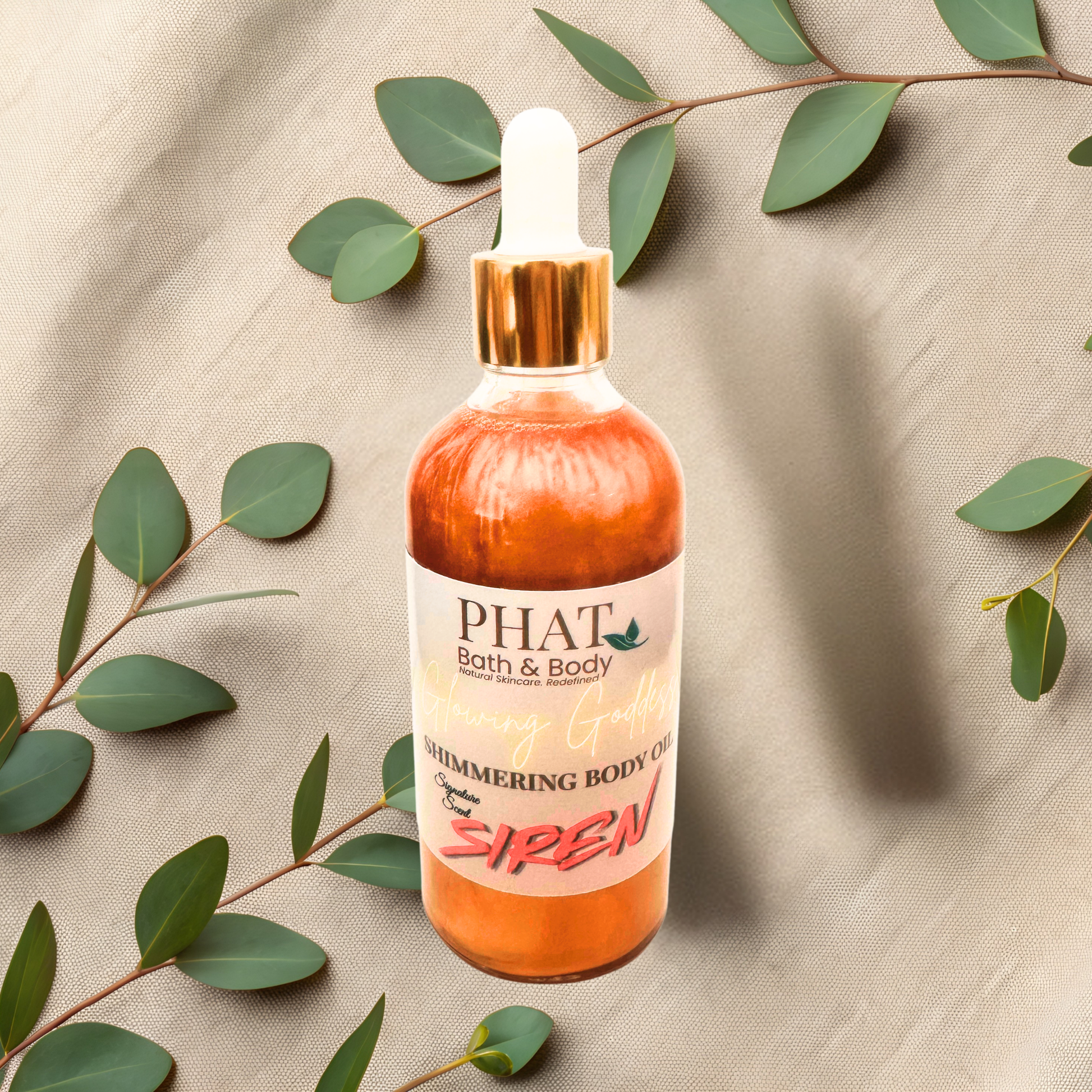 Bottle of PHAT Bath & Body shimmering body oil with green leaves on a beige fabric background