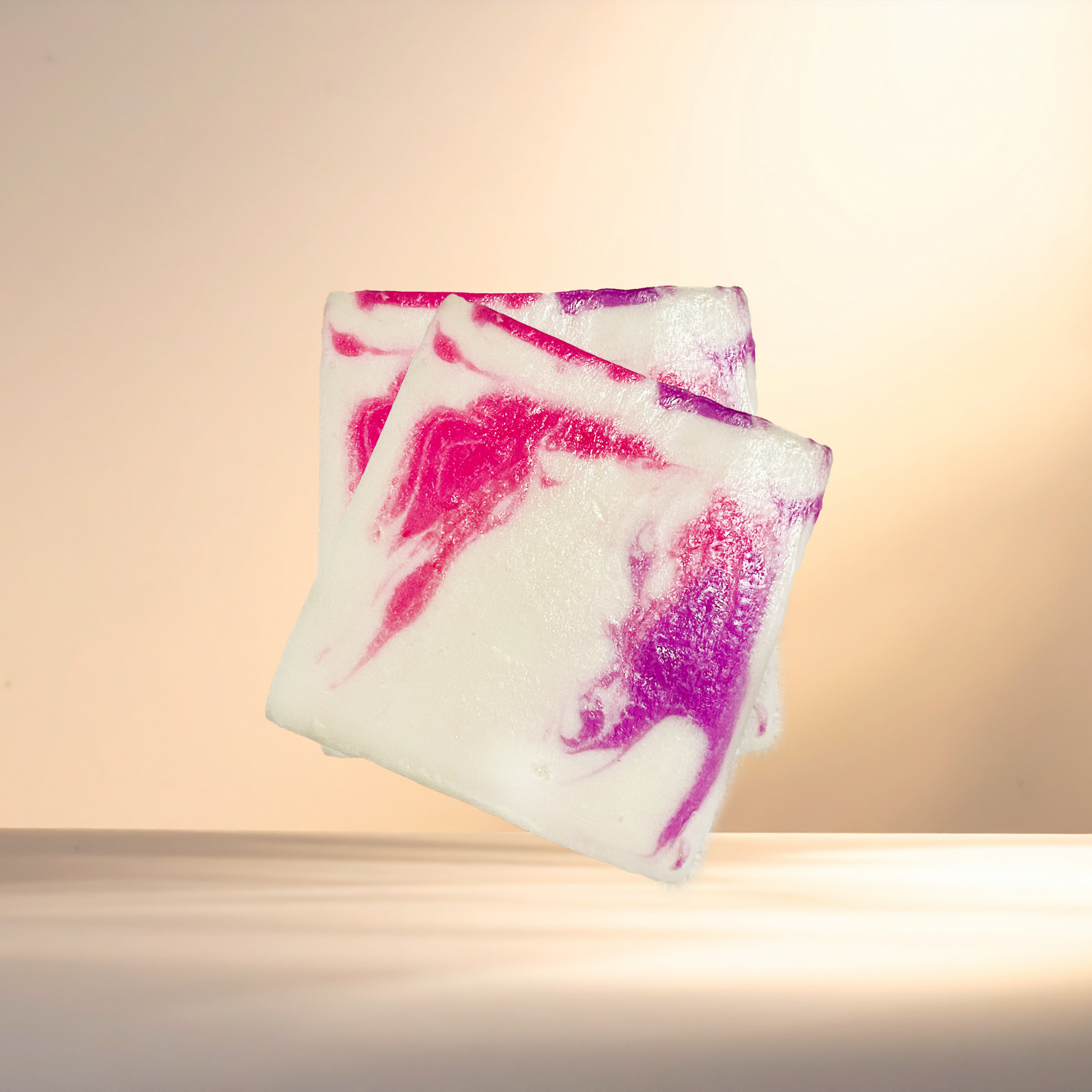 Two colorful soap bars with pink and purple swirls on a beige background