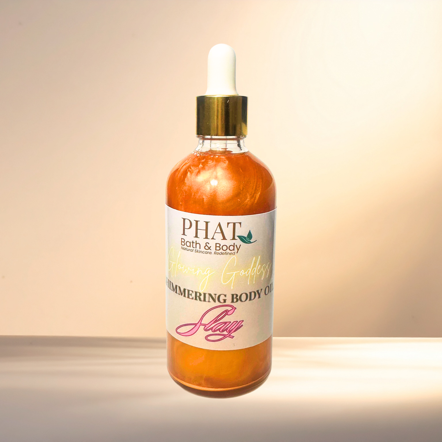 Bottle of 'PHAT Bath & Body' shimmering body oil on a gradient background