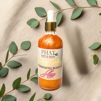 Bottle of 'PHAT Bath & Body' shimmering body oil with green leaves on a beige fabric background